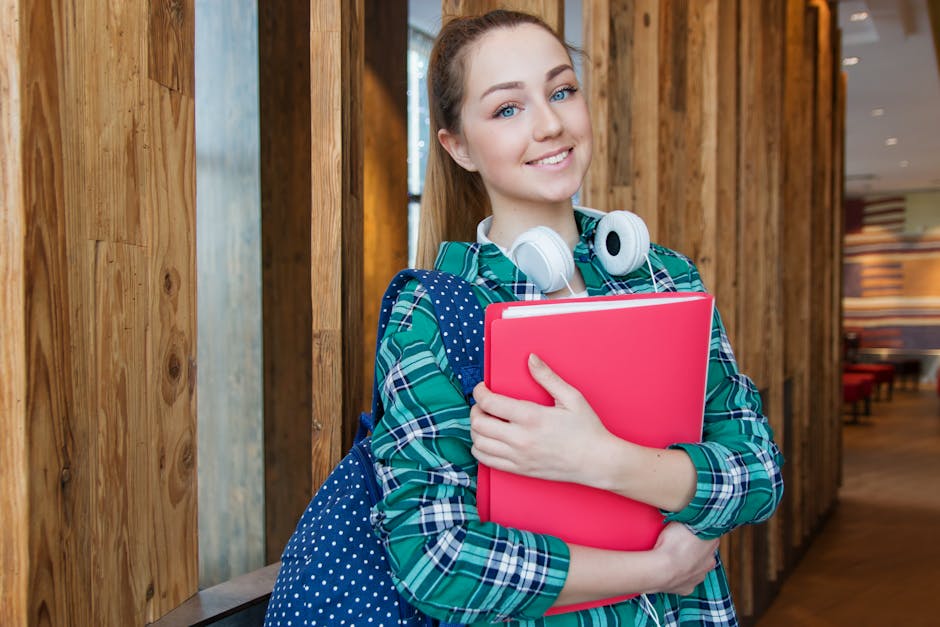 Smiling student holding book and wearing headphones, ready for study